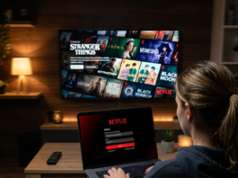 Person signing into Netflix on a laptop facing a television